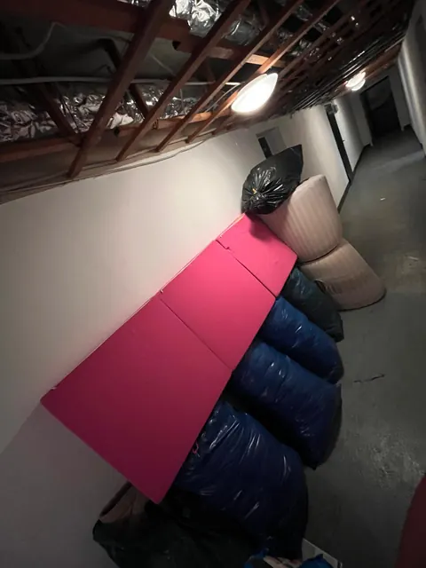 Kellergang mit gefüllten Säcken und Polsterteilen an der Wand