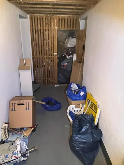 Kellergang mit Kartons, Säcken und Wäschekorb vor der Räumung